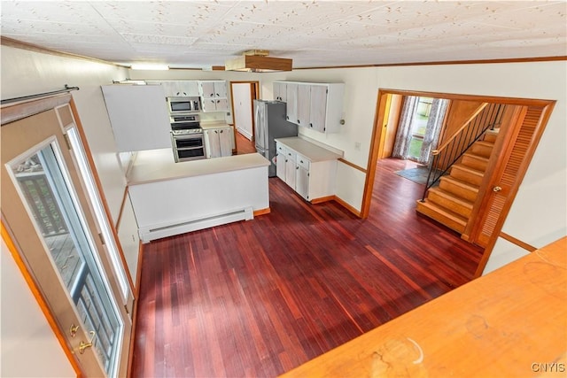 kitchen featuring appliances with stainless steel finishes, dark hardwood / wood-style flooring, vaulted ceiling, a baseboard heating unit, and white cabinetry