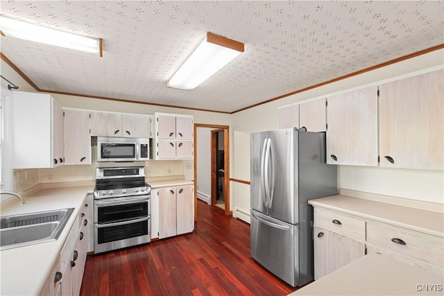 kitchen with appliances with stainless steel finishes, baseboard heating, crown molding, sink, and dark hardwood / wood-style floors