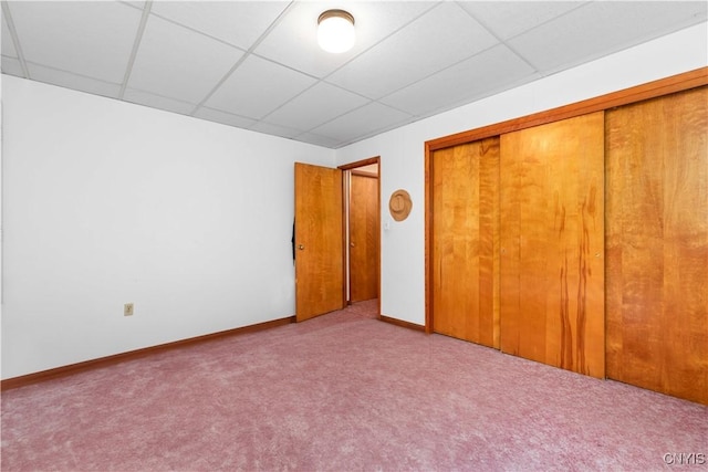 unfurnished bedroom featuring a paneled ceiling, light colored carpet, and a closet