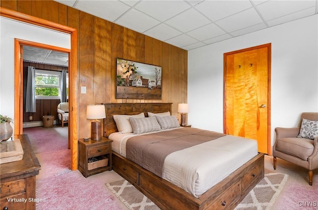 bedroom featuring wood walls, a drop ceiling, and light carpet