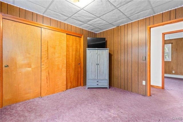 unfurnished bedroom featuring carpet, a closet, and wood walls