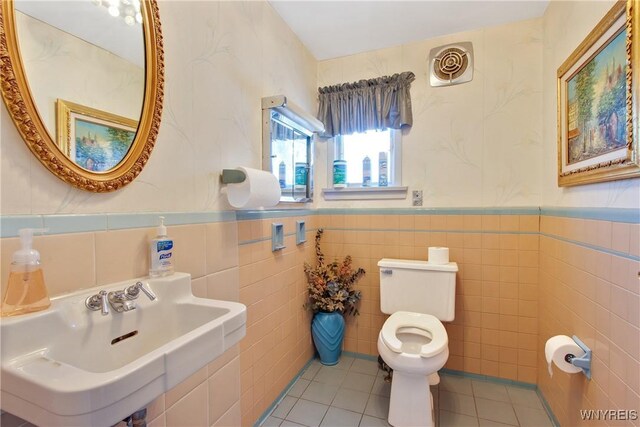 bathroom featuring tile patterned floors, sink, tile walls, and toilet