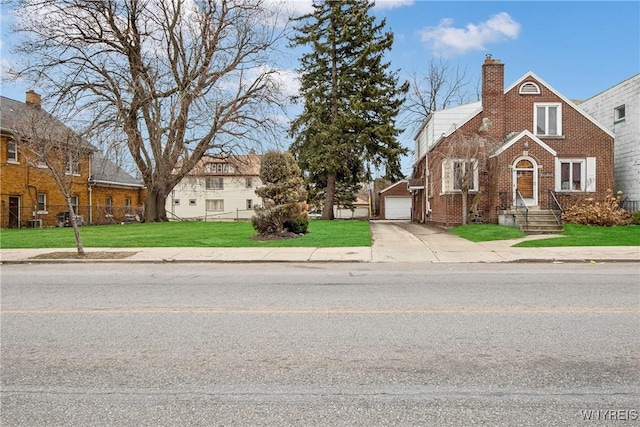 view of front of home with a front lawn, concrete driveway, a garage, brick siding, and a chimney