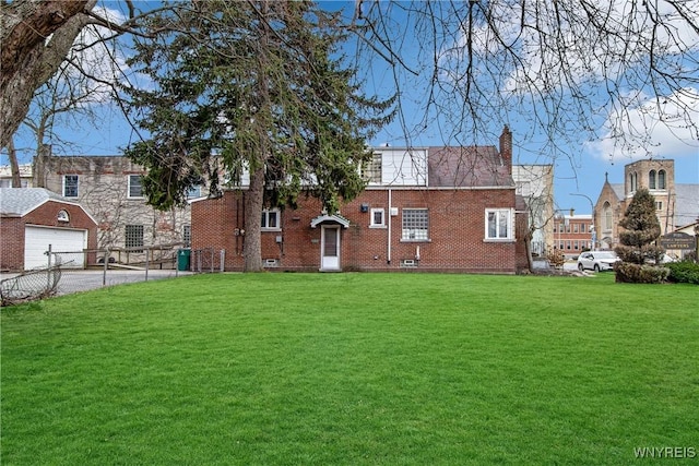 rear view of house featuring a chimney, a garage, aphalt driveway, a lawn, and brick siding