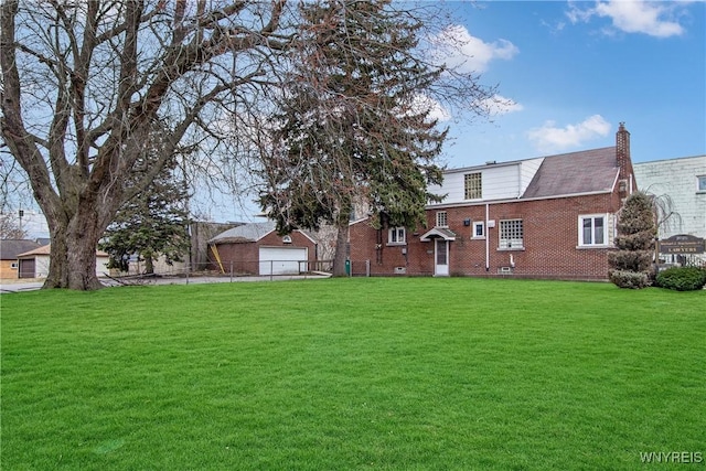 rear view of house featuring brick siding, fence, a lawn, a chimney, and a garage