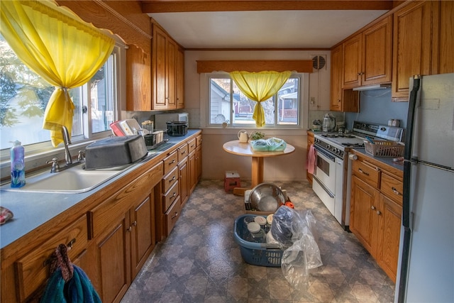 kitchen featuring white range with gas stovetop, decorative backsplash, refrigerator, and sink