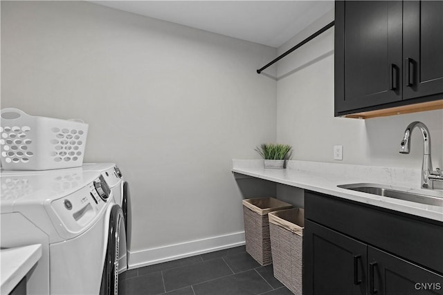 laundry area with cabinets, separate washer and dryer, dark tile patterned floors, and sink