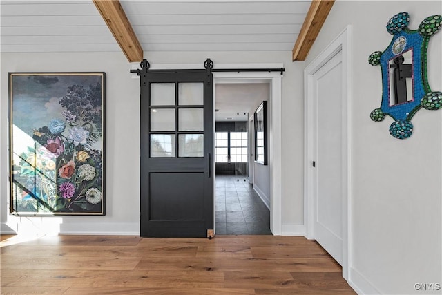 interior space with beam ceiling, a barn door, wood ceiling, and wood-type flooring