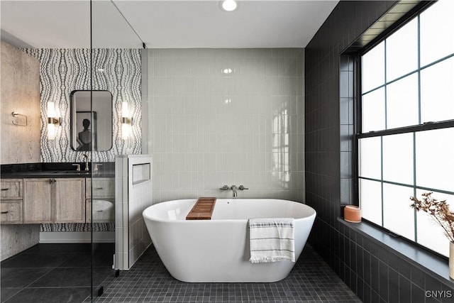 bathroom featuring a tub, tile patterned flooring, vanity, and tile walls