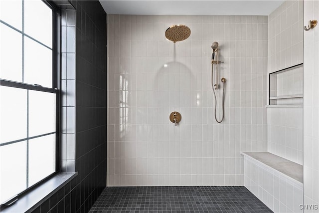 bathroom featuring a tile shower and a healthy amount of sunlight