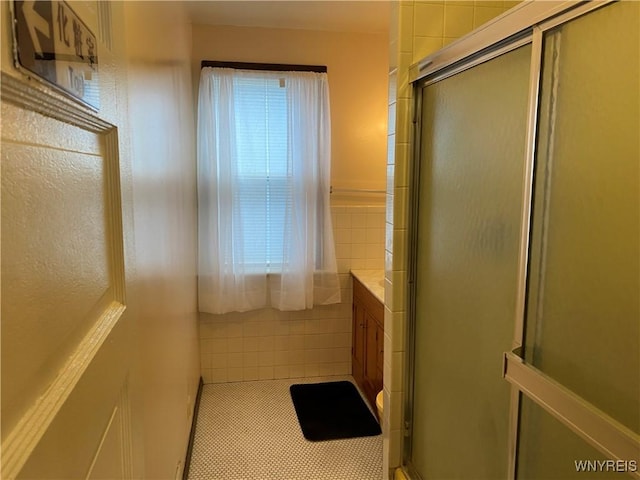 bathroom featuring tile patterned flooring, vanity, tile walls, and walk in shower