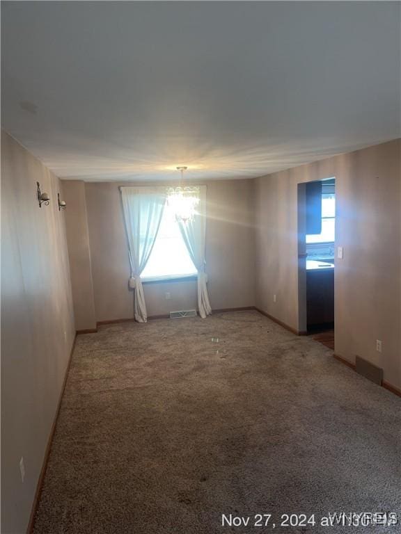 spare room featuring carpet floors and an inviting chandelier