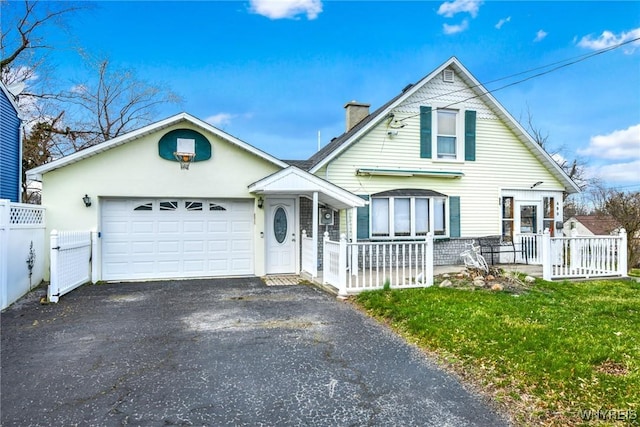 view of front of home featuring covered porch, a garage, and a front yard