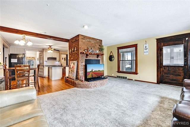 living room featuring beamed ceiling, a fireplace, light carpet, and a textured ceiling