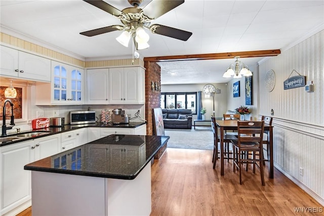 kitchen with light wood-type flooring, dark stone counters, sink, and white cabinets