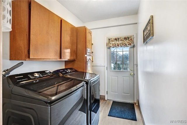 laundry room featuring cabinets, washing machine and clothes dryer, and light hardwood / wood-style floors