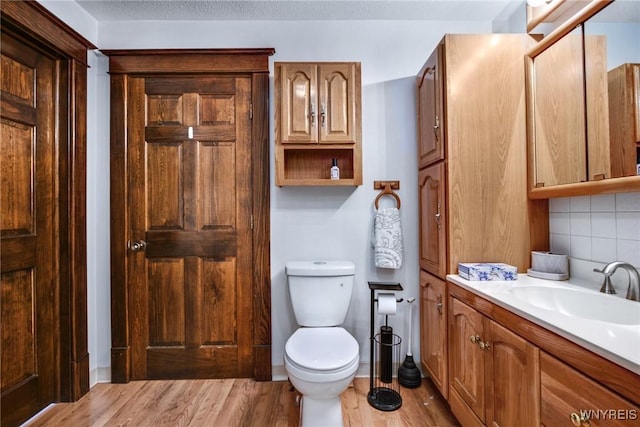 bathroom featuring tasteful backsplash, vanity, wood-type flooring, a textured ceiling, and toilet