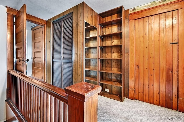 unfurnished office with wooden walls, a textured ceiling, and carpet flooring