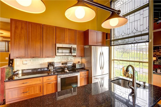 kitchen with appliances with stainless steel finishes, tasteful backsplash, dark stone counters, and sink