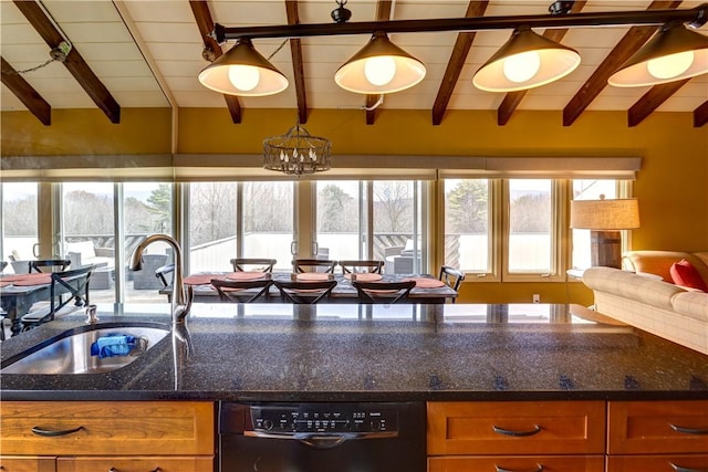 kitchen with dark stone countertops, dishwasher, pendant lighting, and sink