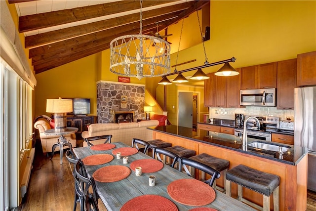 dining area featuring a stone fireplace, dark hardwood / wood-style flooring, beamed ceiling, and high vaulted ceiling