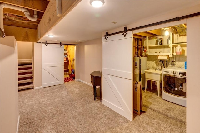 basement featuring light colored carpet, sink, a barn door, water heater, and washer / dryer