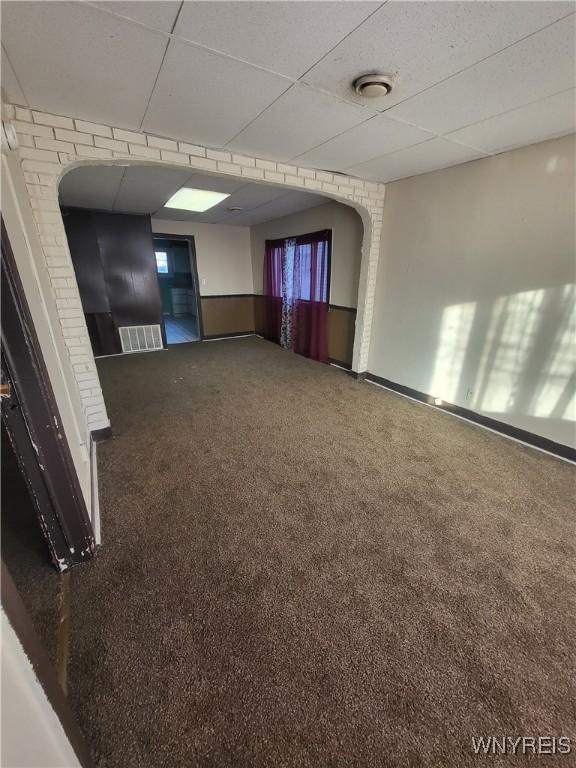 empty room featuring carpet and a paneled ceiling