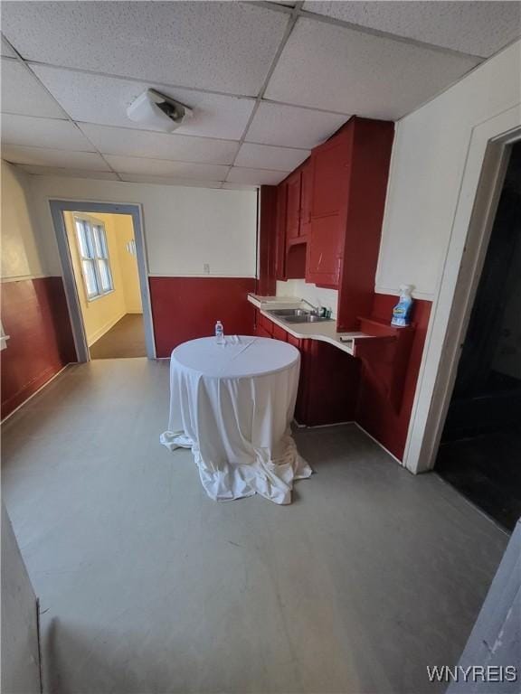 dining room featuring a drop ceiling, concrete flooring, and sink