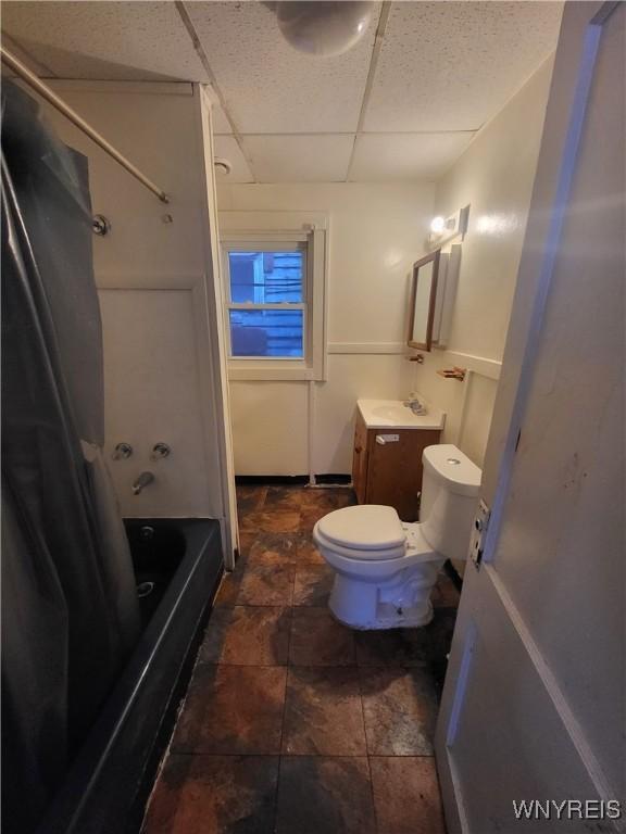 full bathroom featuring a drop ceiling, toilet, vanity, and bathtub / shower combination