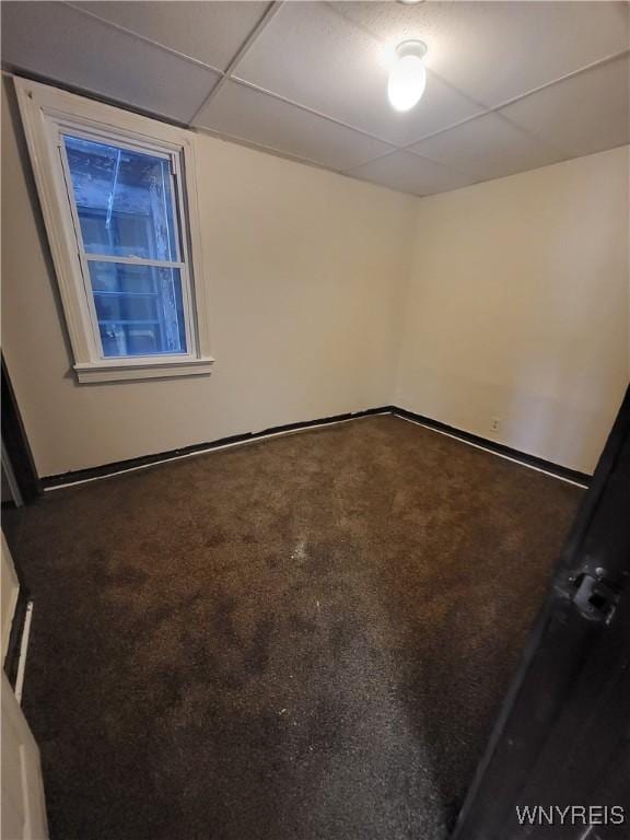 unfurnished room with a paneled ceiling and carpet floors