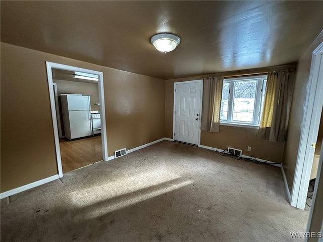 unfurnished bedroom featuring white refrigerator, light colored carpet, and a closet