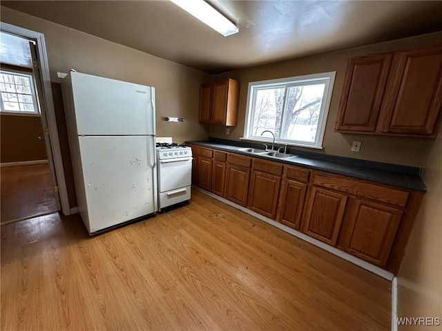 kitchen featuring light wood-type flooring, white appliances, and sink