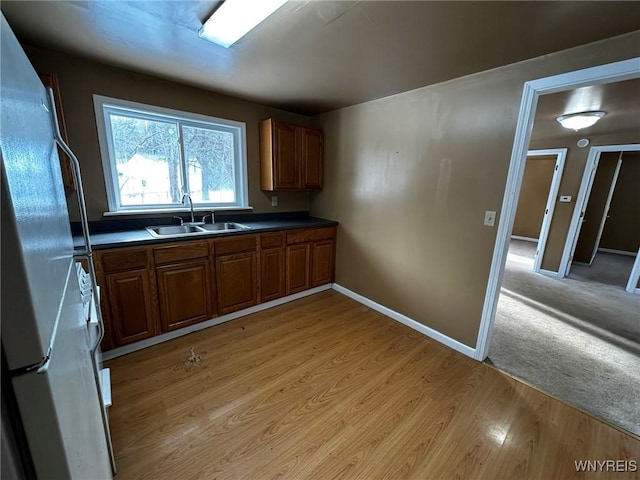 kitchen featuring sink, white fridge, and light wood-type flooring