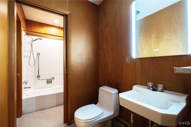 full bathroom with toilet, washtub / shower combination, sink, and wooden walls