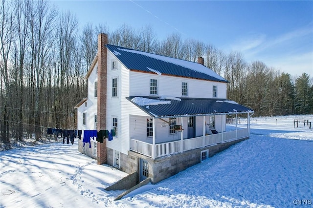 snow covered back of property with a porch