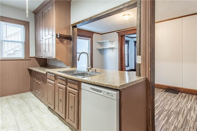 kitchen featuring wooden walls, sink, white dishwasher, and ornamental molding