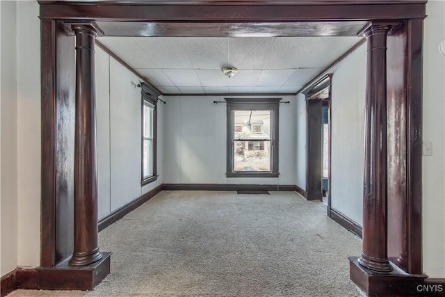 empty room featuring ornate columns and light colored carpet