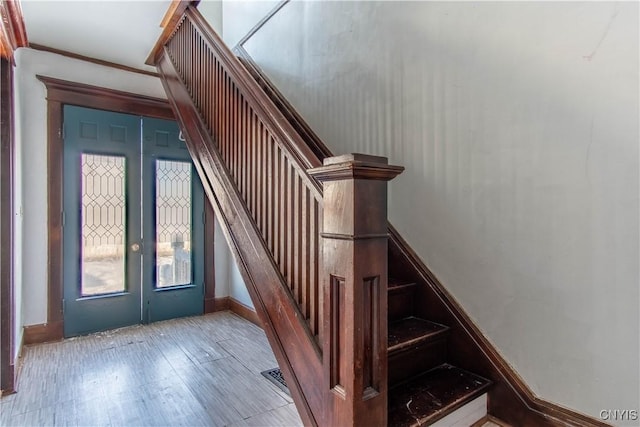 staircase with crown molding and wood-type flooring