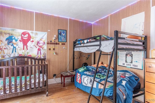 bedroom with wood walls and light wood-type flooring