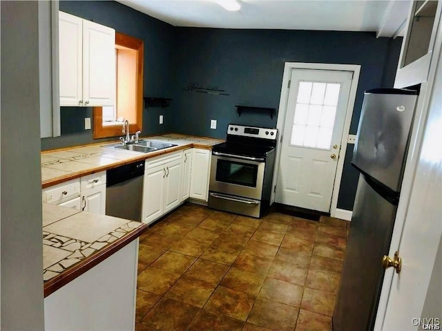 kitchen featuring sink, kitchen peninsula, appliances with stainless steel finishes, tile counters, and white cabinetry