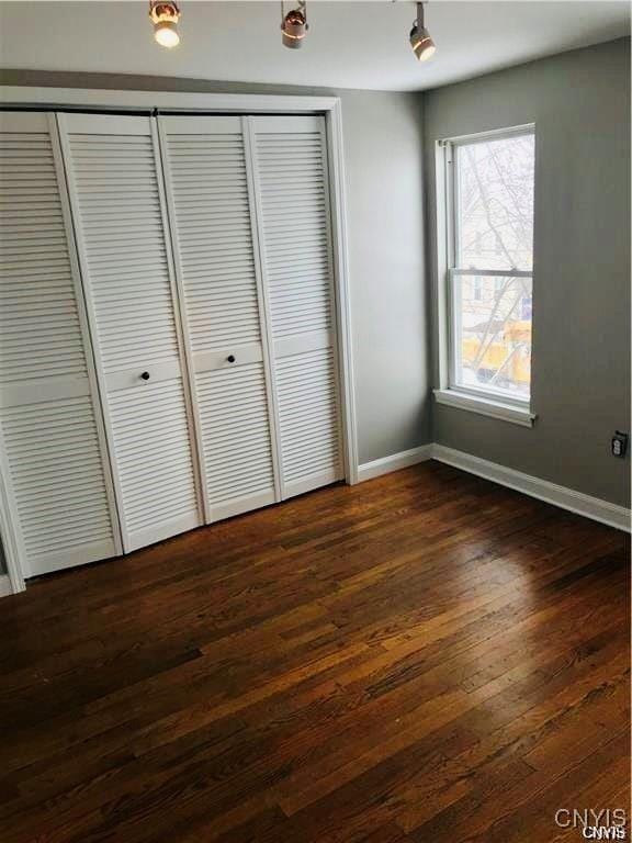 unfurnished bedroom featuring a closet and dark wood-type flooring