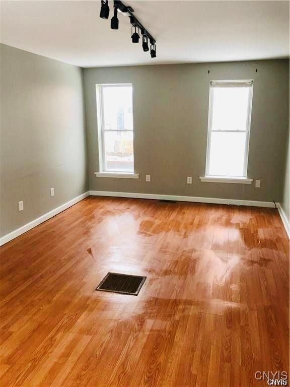 spare room with light hardwood / wood-style floors and rail lighting