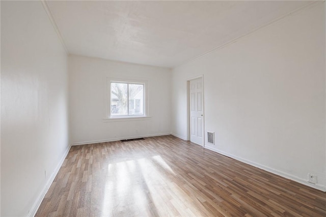 empty room featuring wood-type flooring and crown molding