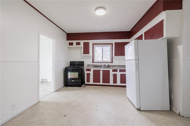 kitchen with black range with gas stovetop, sink, and white fridge