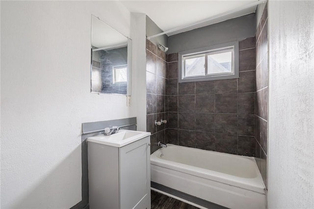 bathroom with hardwood / wood-style flooring, vanity, and tiled shower / bath