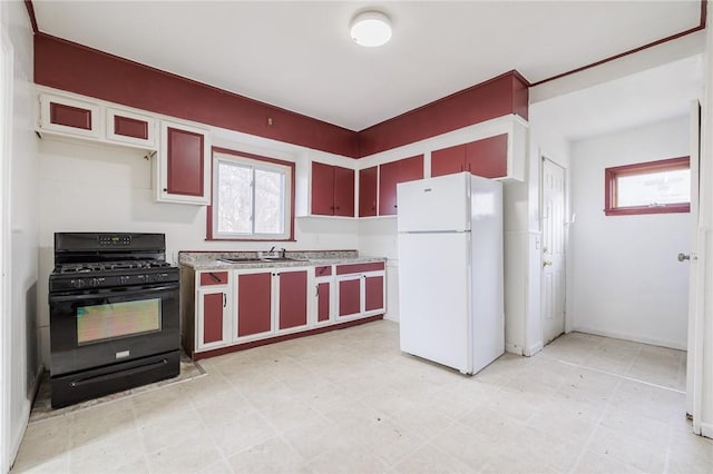 kitchen with black range with gas stovetop, white fridge, and sink