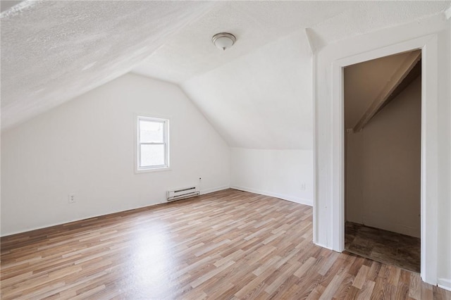 bonus room featuring light wood-type flooring, a textured ceiling, and a baseboard heating unit