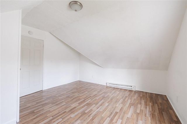 additional living space featuring light hardwood / wood-style floors, vaulted ceiling, and baseboard heating