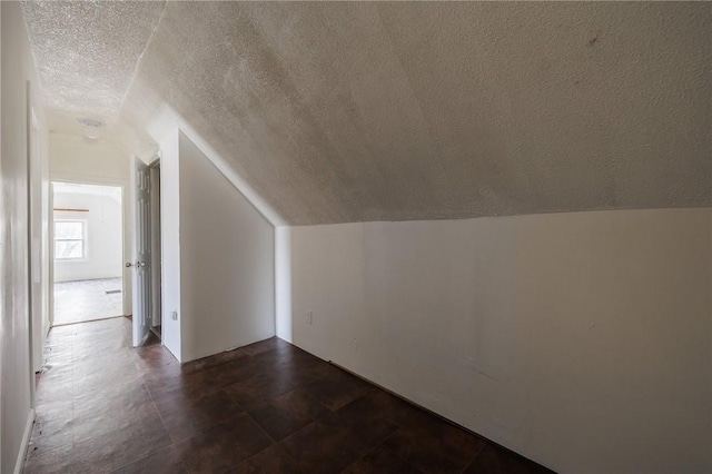 additional living space with lofted ceiling and a textured ceiling