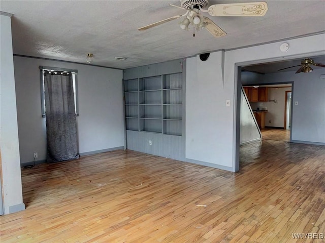 empty room featuring ceiling fan, light hardwood / wood-style floors, and a textured ceiling